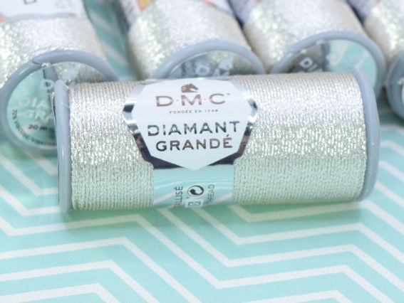 Котушка срібного люрексу DMC Diamant Grande великим планом, де чітко видно текстуру намотування, фірмову наклейку з логотипом бренду та маркування кольору.