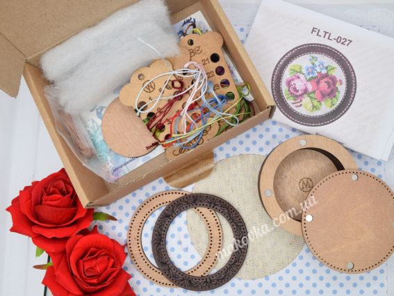 Детальна комплектація набору Wonderland Crafts FLTL-027: розпакована коробка з органайзером для ниток муліне, фанерними деталями корпусу, рамкою зі штучної шкіри, канвою Zweigart та інструкцією на фоні червоних троянд.