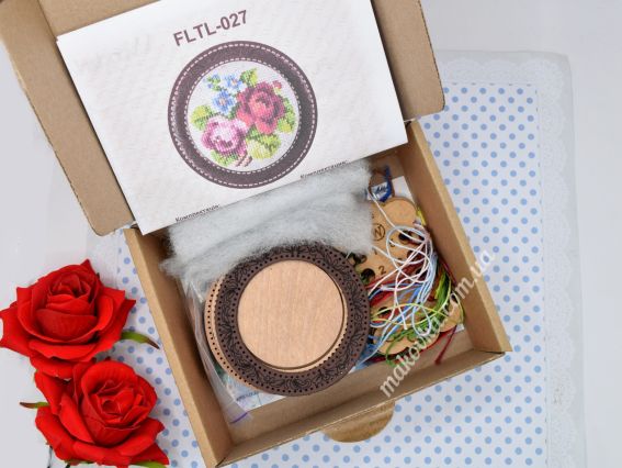 Відкрита коробка з набором для творчості Wonderland Crafts FLTL-027: усередині видно схему вишивки, дерев'яні деталі гольниці-скриньки, нитки муліне та синтепон на фоні декоративних червоних троянд.