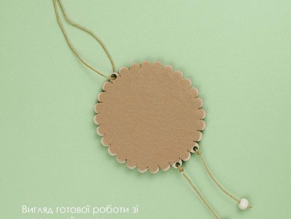  Зворотний бік готової вишитої фігурки баранчика на ніжно-зеленому тлі. Видно кругла основа, акуратно приклеєний коричневий фетр за формою заготовки та підвісні нитки з намистинами.