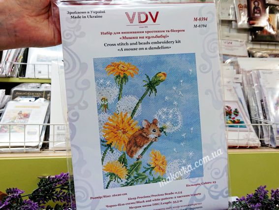 Набір для вишивки VDV «Мишка на кульбабі» в оригінальній упаковці на фоні полиць магазину з товарами для рукоділля.